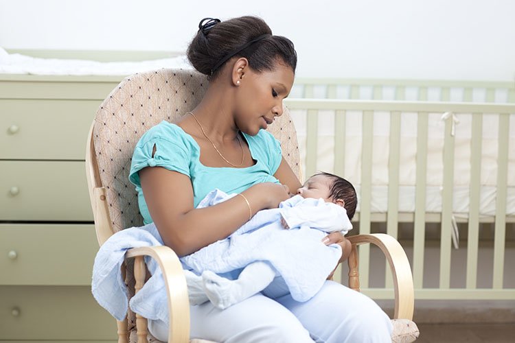 Mother breastfeeding her newborn baby sitting in a chair